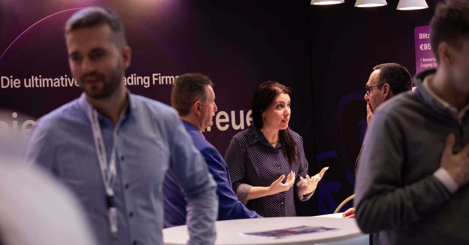 Un groupe de personnes à un stand, une femme parle et gesticule.