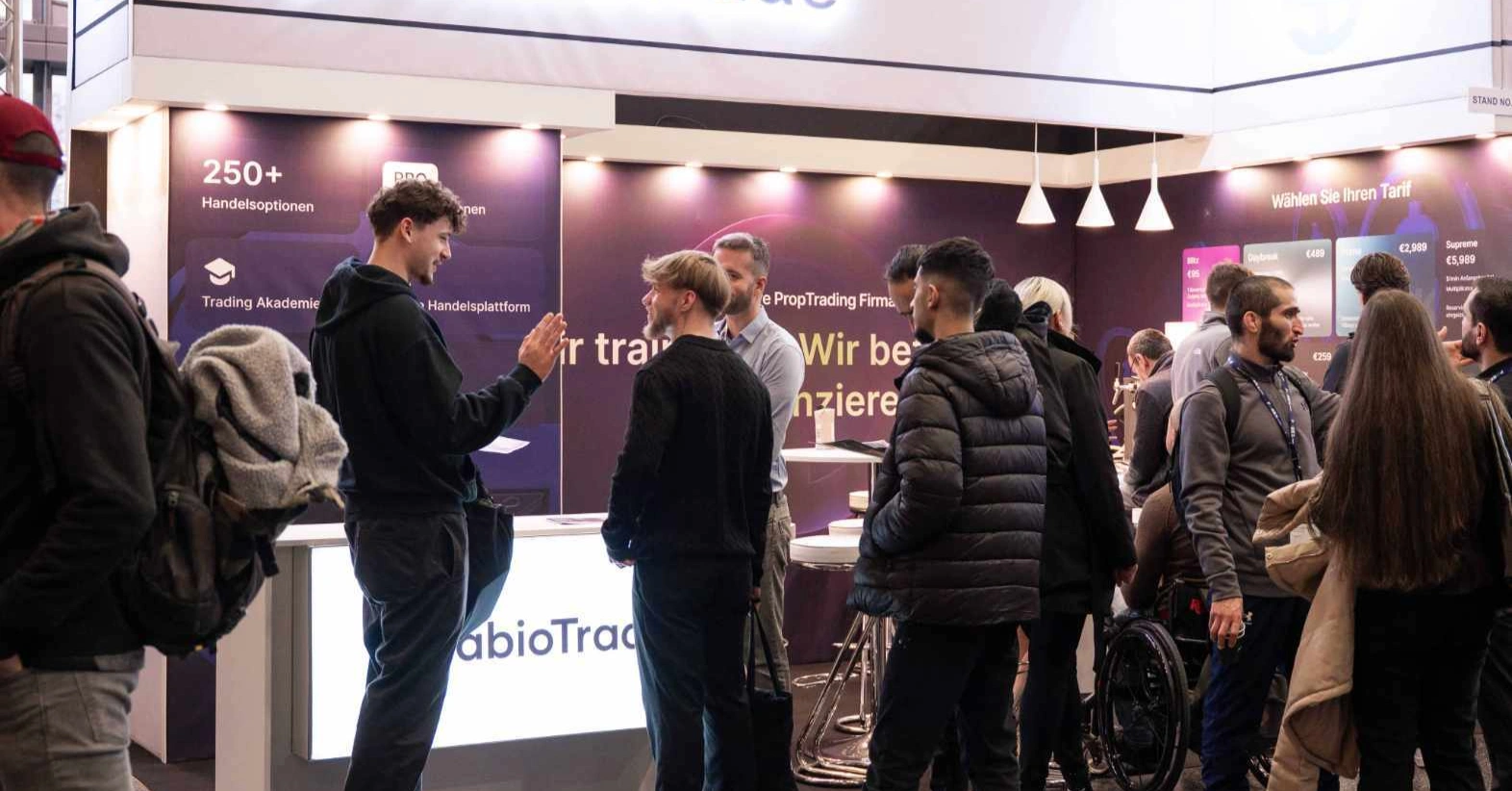 Des personnes se rassemblent autour d'un stand arborant la marque SabioTrade, en discussion.